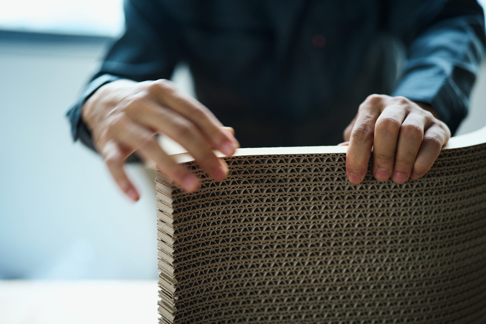 素材 / 積層ダンボールに触れる手のクローズアップ